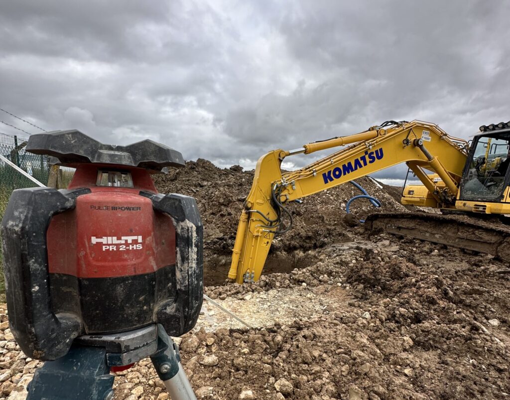Tracked dumper transporting earth on a construction site with fencing and machinery in the background.